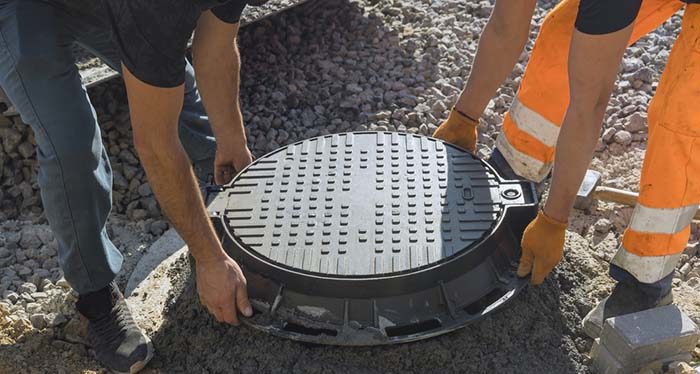 Men lifting septic hole cover